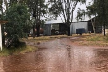 A wet and muddy dirt track in front of a shed
