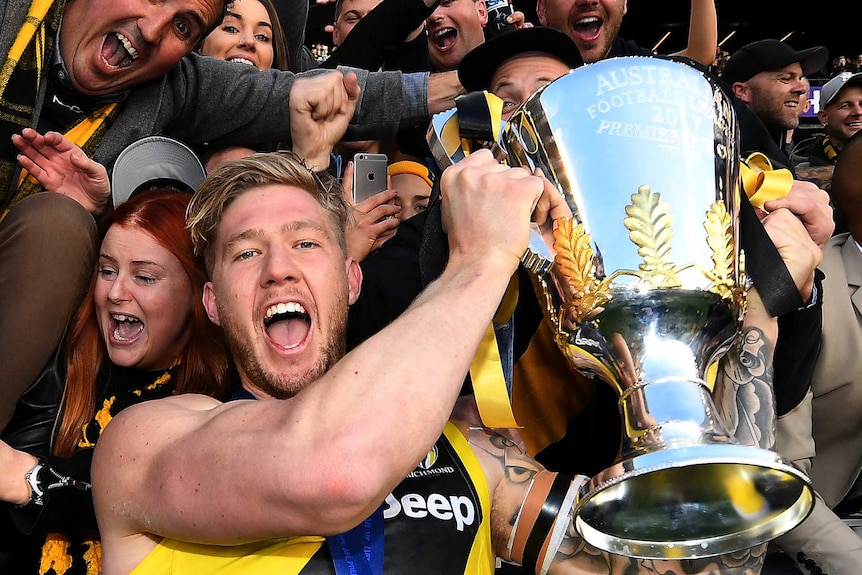 Nathan Broad holds up the 2017 AFL premiership cup, surrounded by fans.