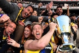 Nathan Broad holds up the 2017 AFL premiership cup, surrounded by fans.