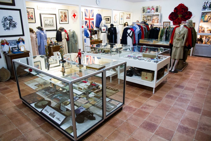 A room filled with glass cabinets of objects and Red Cross uniforms