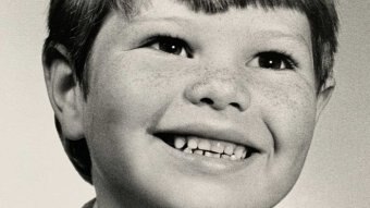 A black-and-white photo of a young smiling boy.