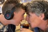 A boy with a disability sharing a soft drink with his mother