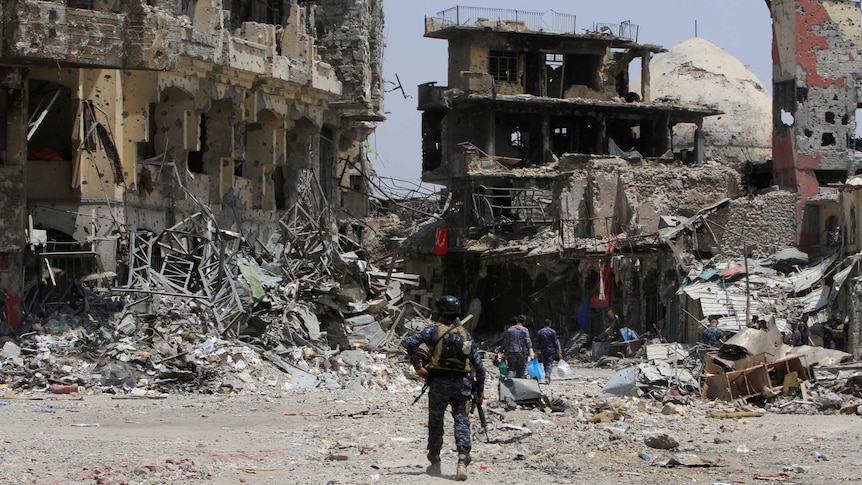 A member of the Federal Police walks through a street of destroyed buildings