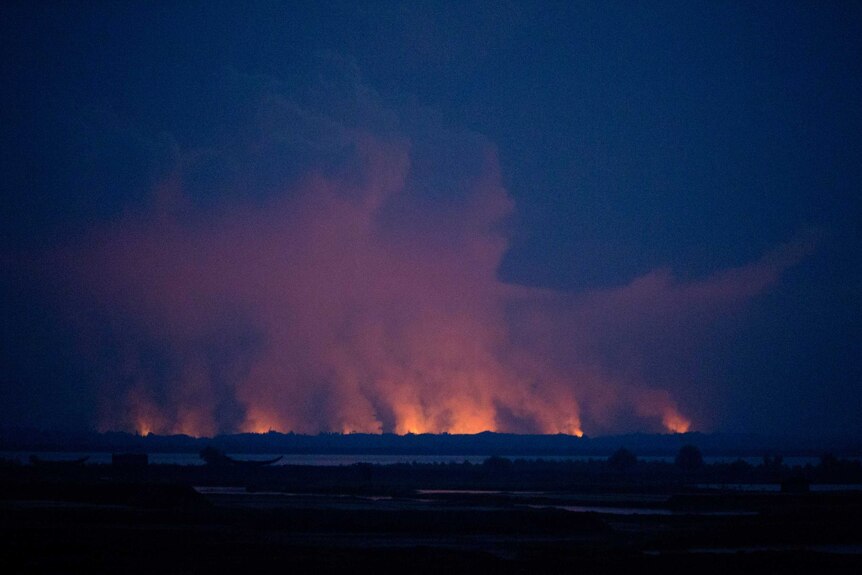 Flames and smoke in Myanmar's Rakhine state illuminate the sky at night.