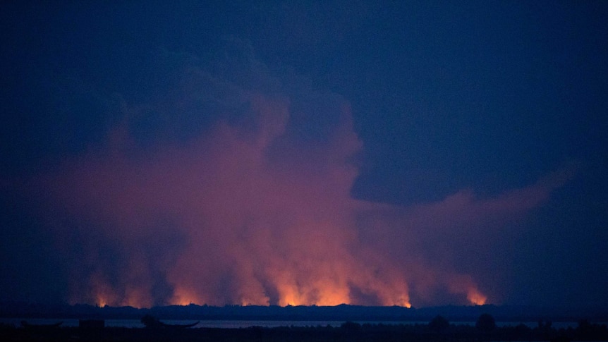 Flames and smoke in Myanmar's Rakhine state illuminate the sky at night.