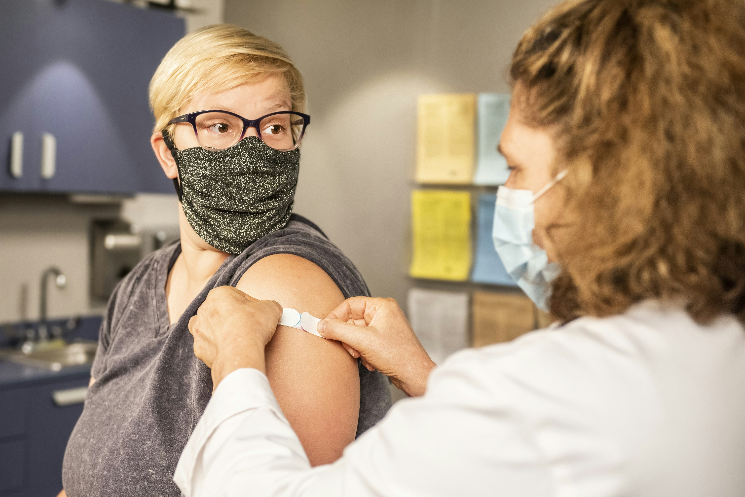 A health worker puts a bandaid over a spot where someone was vaccinated.