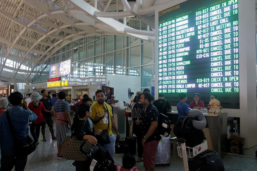 Passengers are seen standing outside the international airport terminal in Bali.