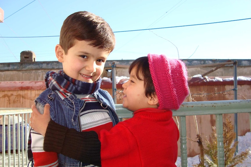 To young children standing on a balcony smiling