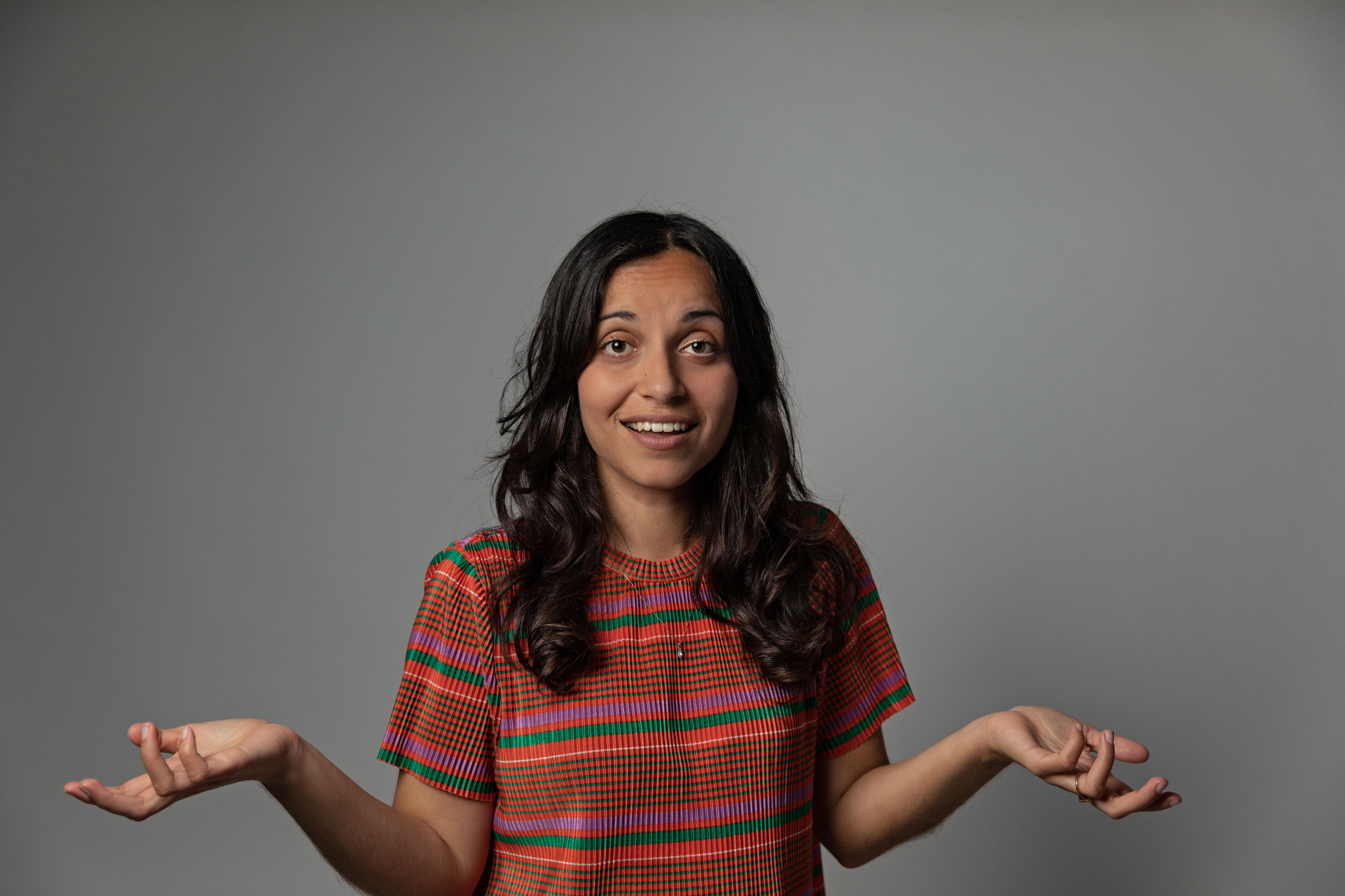 Woman looking to camera with hands out in the style of a shrug.