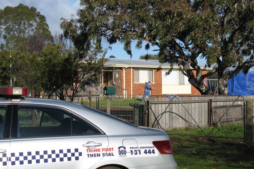 Police officer in blue suit outside house of Shane Barker, Campbell Town murder victim.