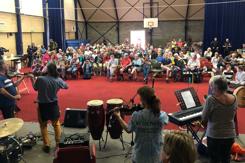 Musicians playing on stage with audience looking on.