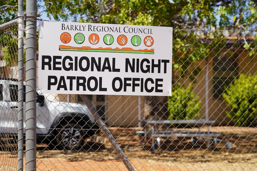 A sign for the Barkly council night patrol office, on a wire fence in front of a building.