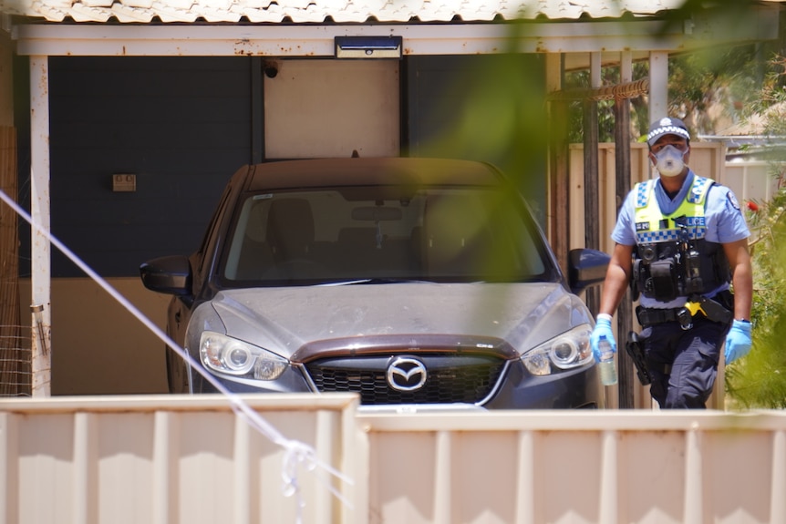 A police officer stands next to a car parked at a house