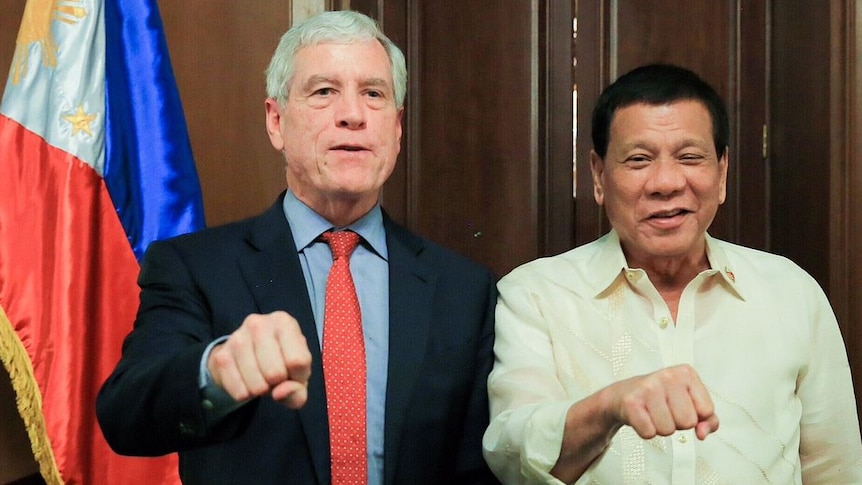 Nick Warner and Rodrigo Duterte pose with their first clenched and held out.