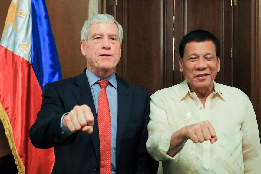 Nick Warner and Rodrigo Duterte pose with their first clenched and held out.