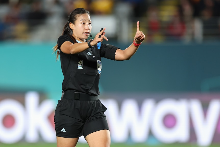 A referee at the Women's World Cup holds up a finger to signal a review of a goal.