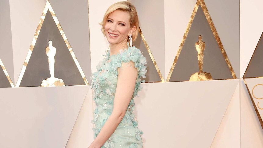 Full length photo of Cate Blanchett on the red carpet in a full length, aqua green gown with adornments.
