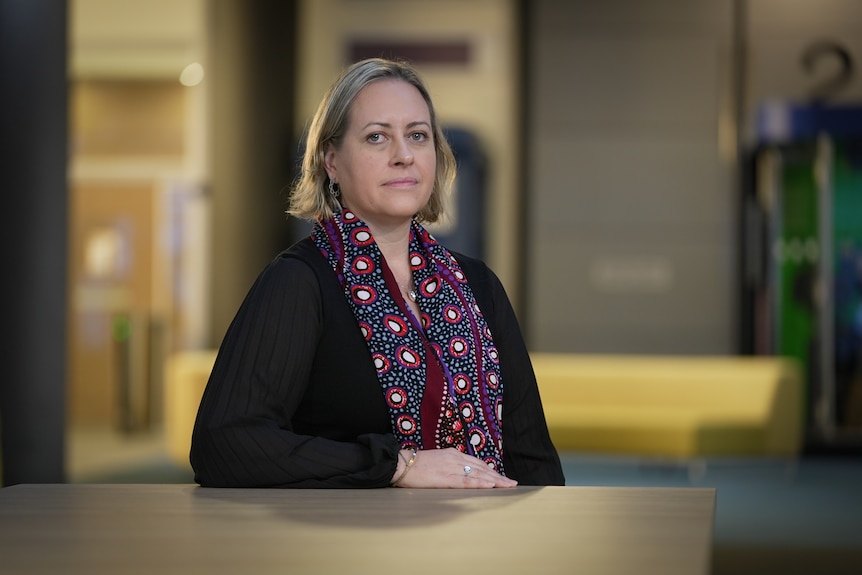 Alison Weatherstone wearing a scarf with circular patterns, looking pensively at the camera. 