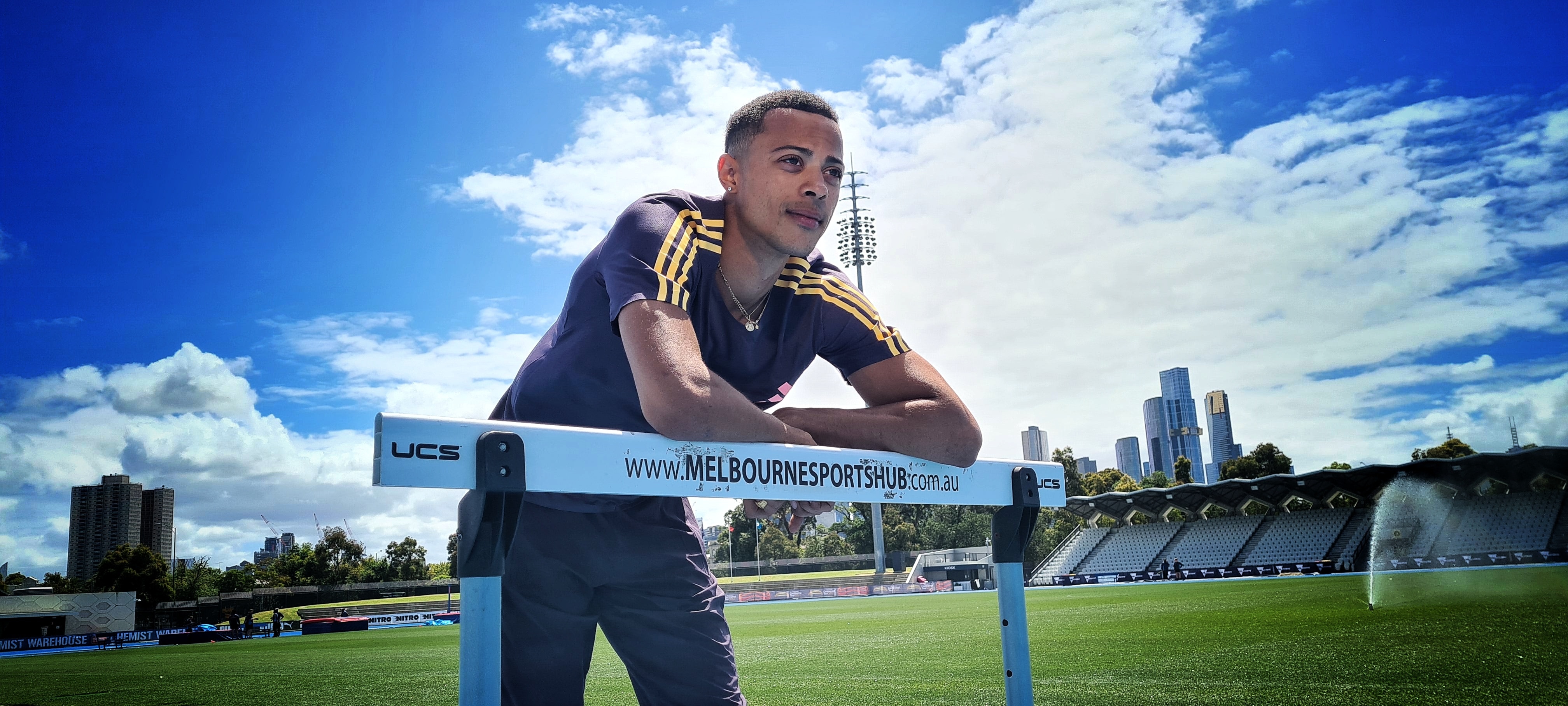 A man poses on a hurdle