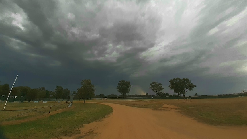 grey dark clouds over a dirt road and field in the southern Riverina in new south wales