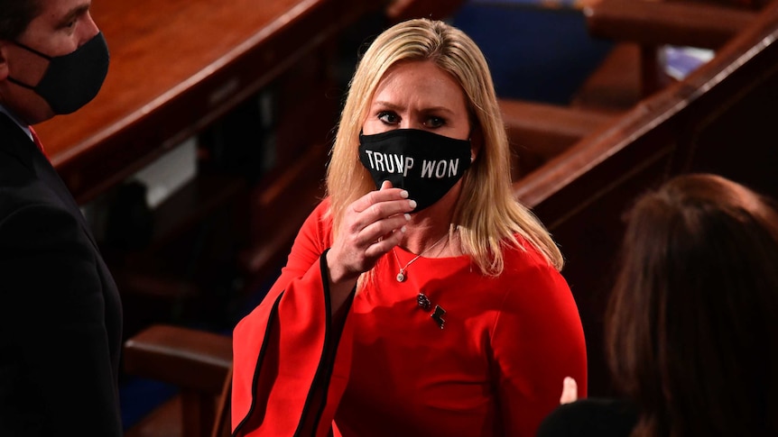 Blonde woman in black mask that says Trump Won, standing in US House of Representatives