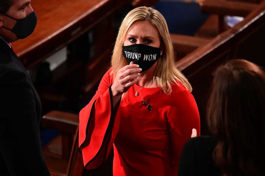 Blonde woman in black mask that says Trump Won, standing in US House of Representatives