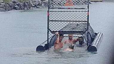 Four men climb into a baited crocodile trap at the Port Douglas marina in far north Queensland.