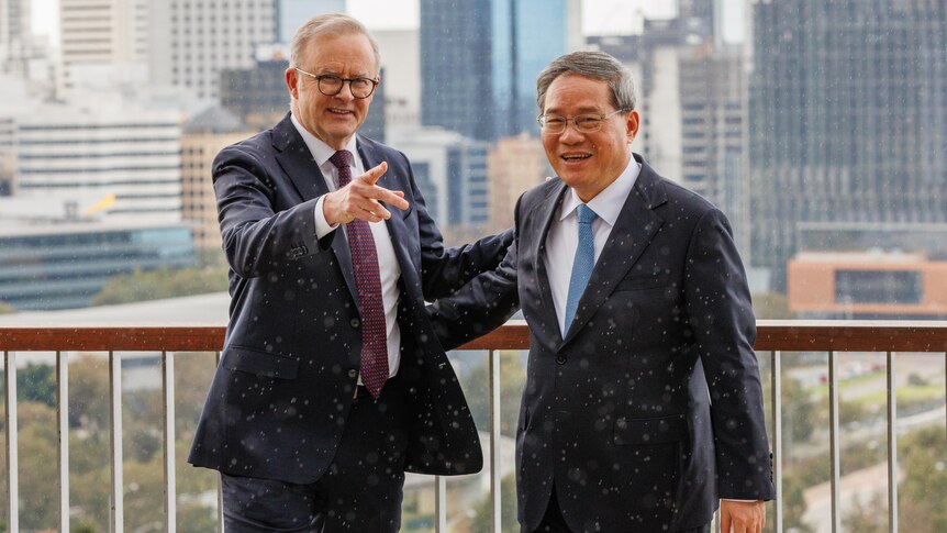 The prime minister and Chinese PM stand at a lookout with a city skyline in the background