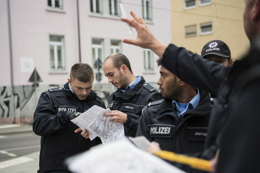 Officers look at maps and plans ahead of the disposal in a frankfurt street