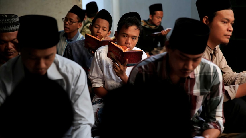 Children with religious headwear read from identical books