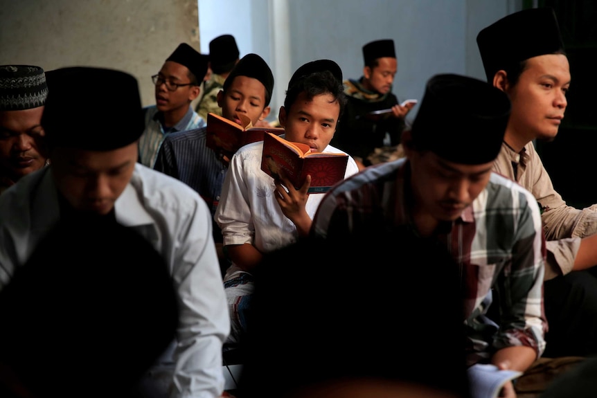 Children with religious headwear read from identical books