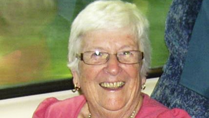 Woman smiling at camera while sitting in a seat on a bus