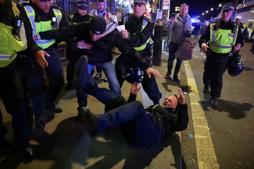 Police officers detain a counter-protester in London.