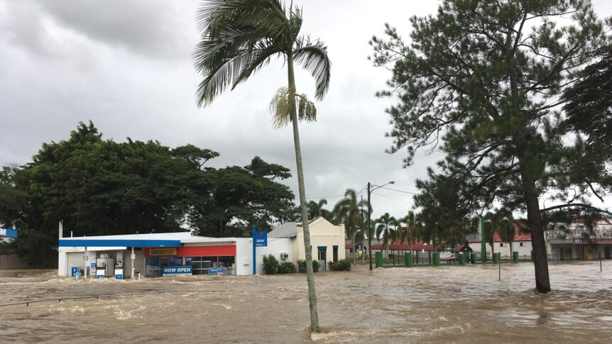 Floodwaters cover the road up to the front of the service station and shops at Ingham