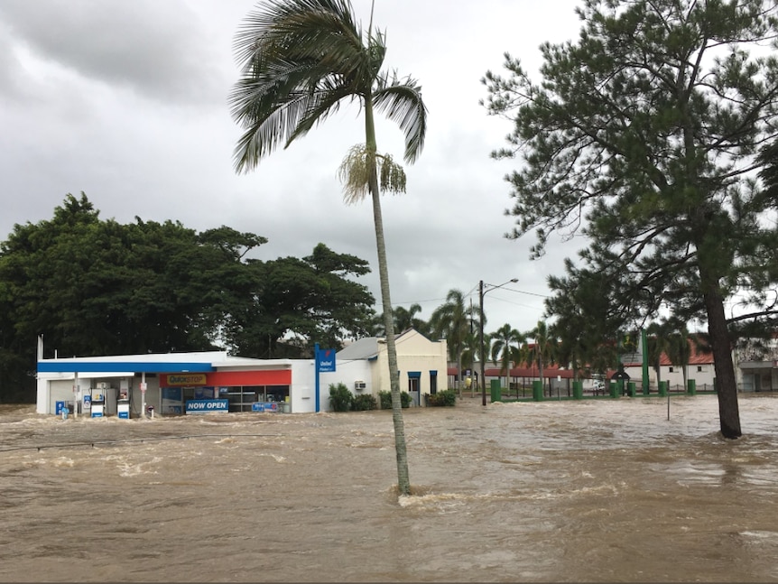 Floodwaters cover the road up to the front of the service station and shops at Ingham