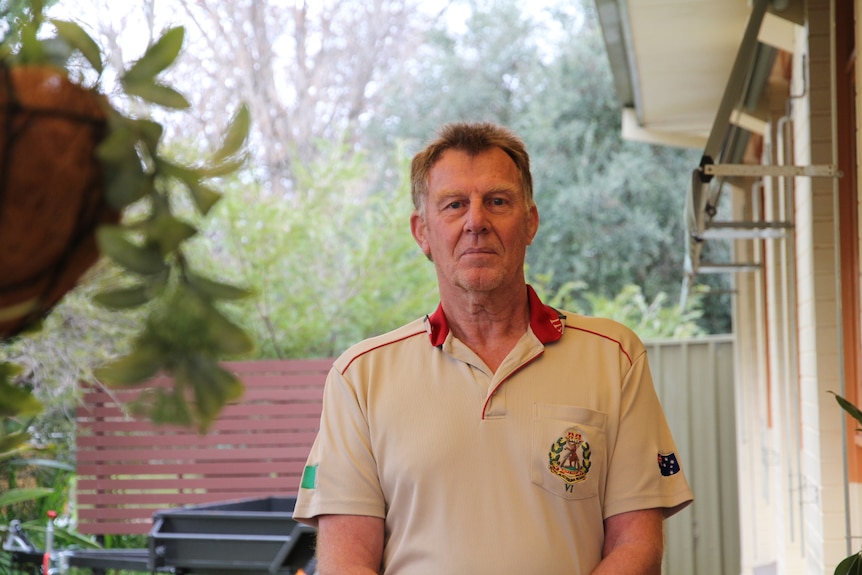 A man standing towards the camera in the courtyard of their home.