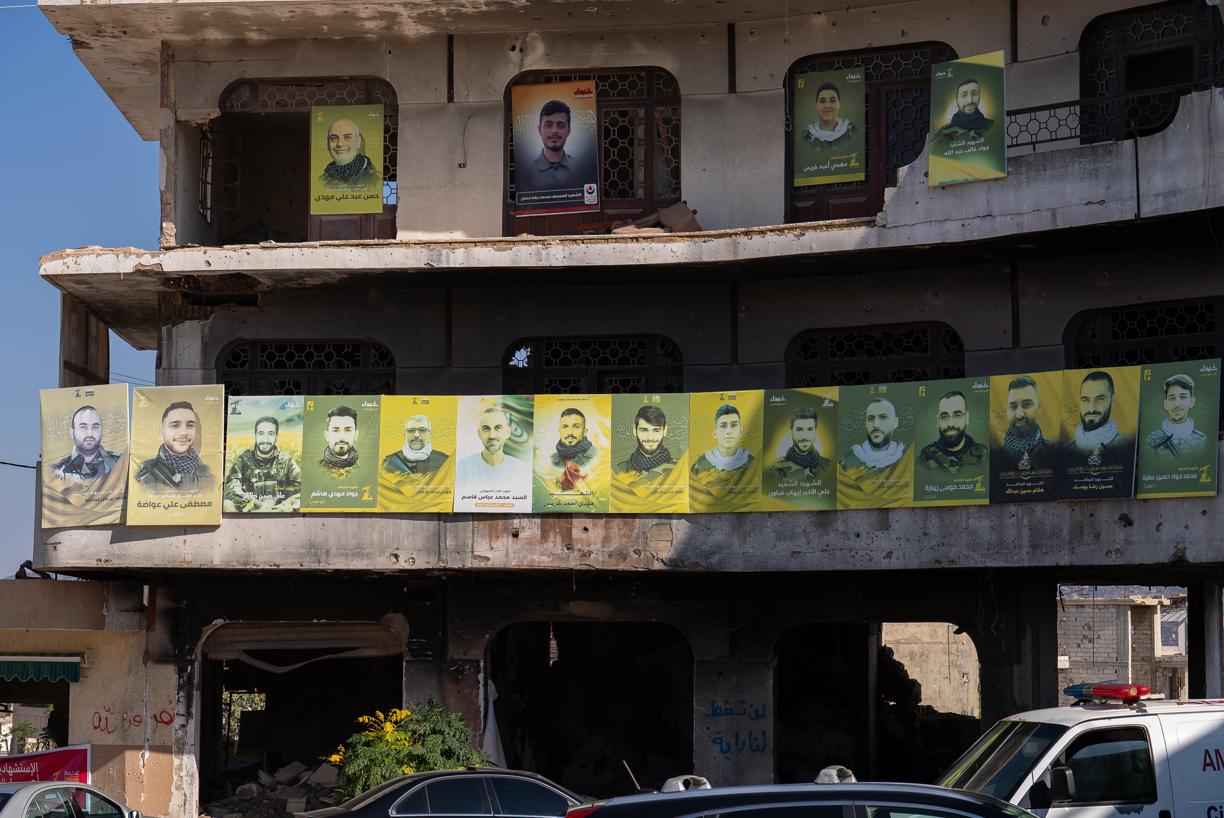 Green and yellow portraits of men lining a building.