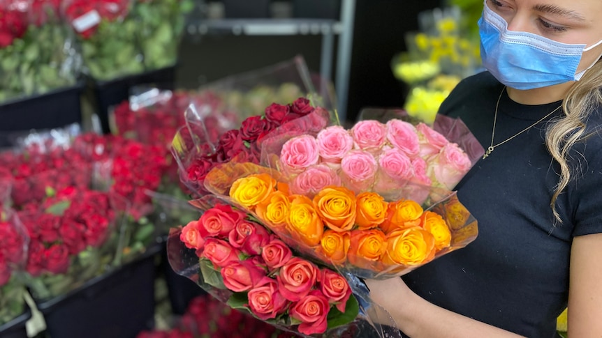 Bunch of roses held by woman wearing mask