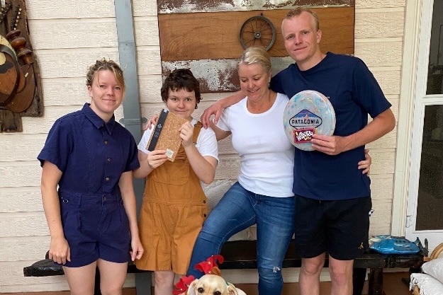 Interior scene of Poppy, siblings, mum and dog holding Christmas presents