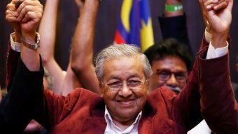 Mahathir holds his hands up in celebration.