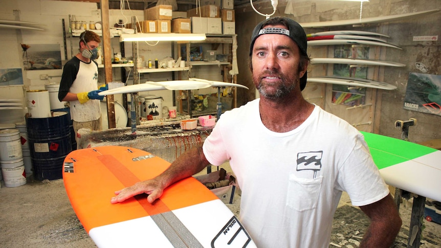 A man stands in his surfboard making workshop