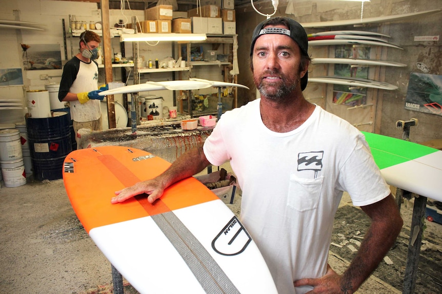 A man stands in his surfboard making workshop