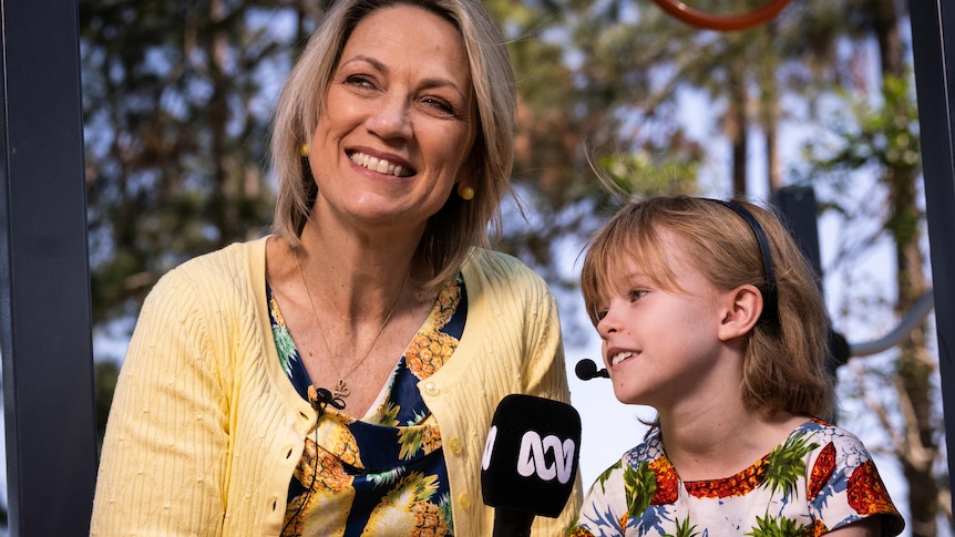 A woman holding an ABC microphone interviews a young girl.