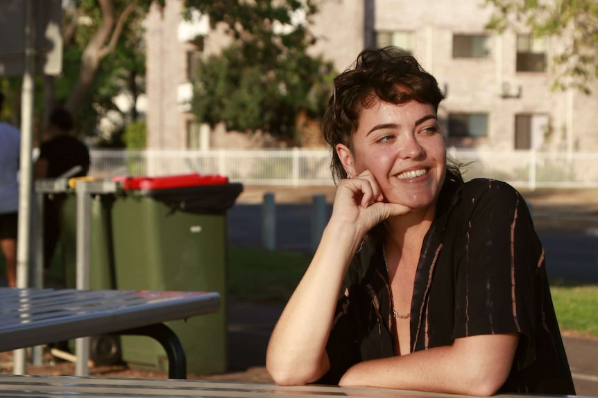 A photo of former Melbourne resident Anna McDermott at a table in Nightcliff on a sunny afternoon.