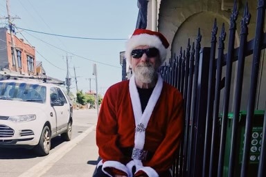 A man dressed as Santa outside an inner-city home.