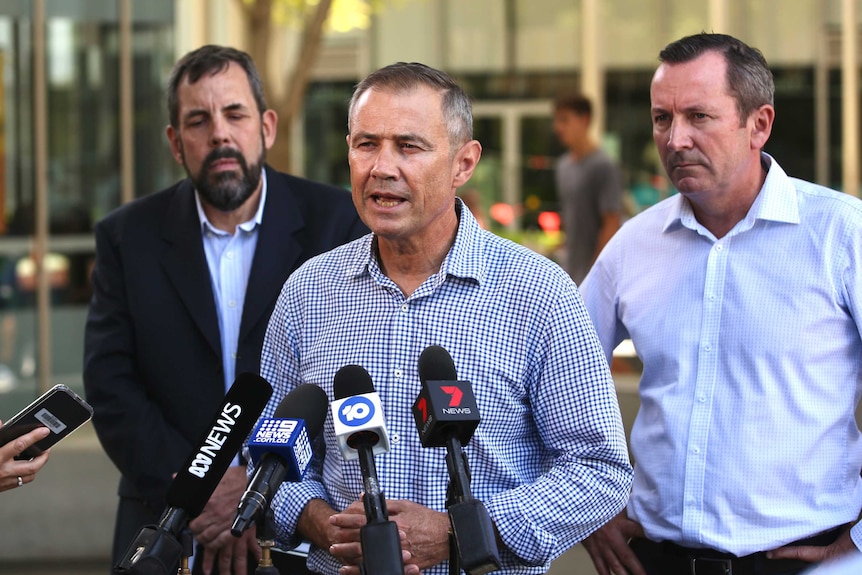 Roger Cook delivers a media conference with Dr Andrew Roberston and Mark McGowan standing behind him