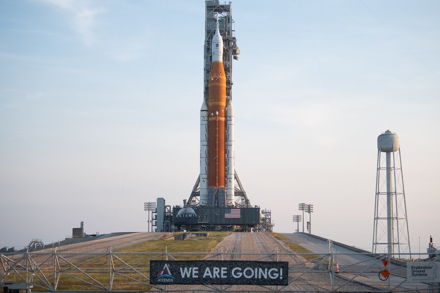 A rocket sits on top of a hill, with a sign saying 'WE ARE GOING!'