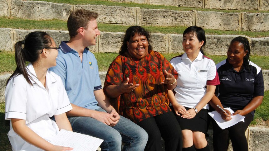 Curtin University students surround an Indigenous woman as part of an interprofessional learning program