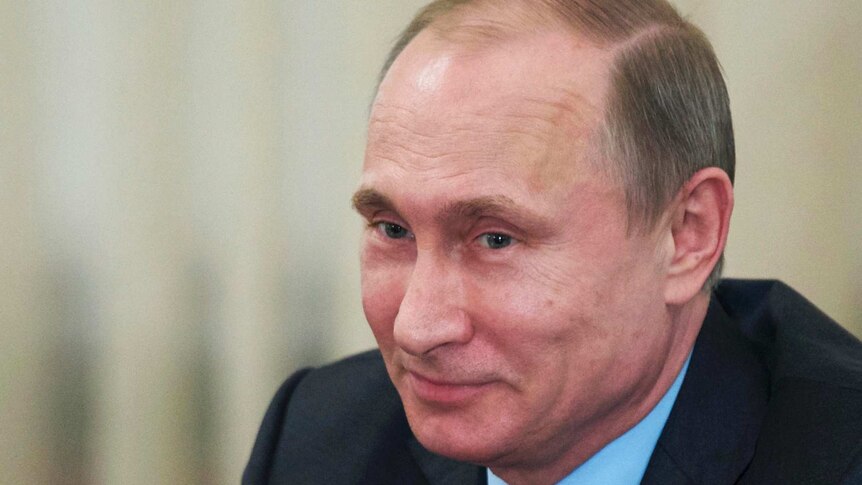 Russian President Vladimir Putin smiles during a meeting.