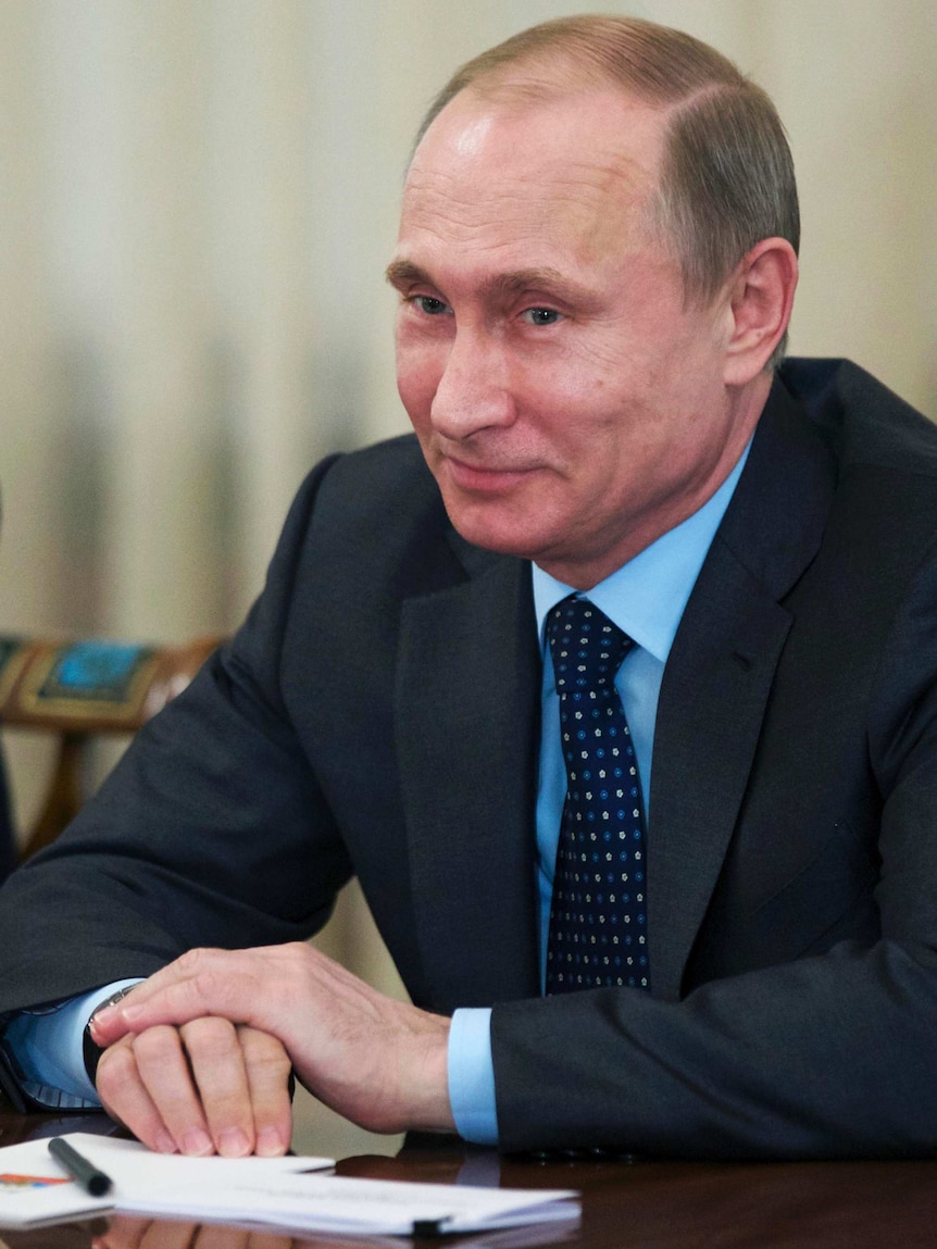 Russian President Vladimir Putin smiles during a meeting.